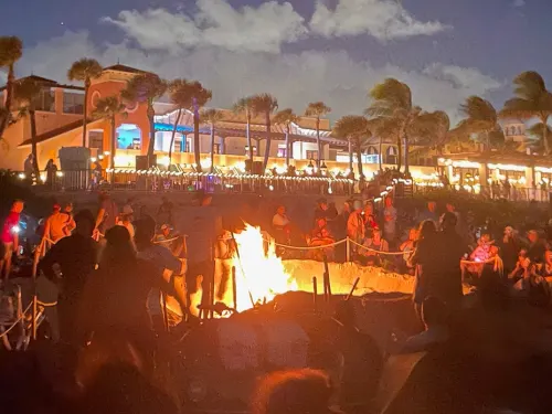 Bonfire burning on beach with dusk sky in the background.