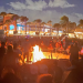 Bonfire burning on beach with dusk sky in the background.